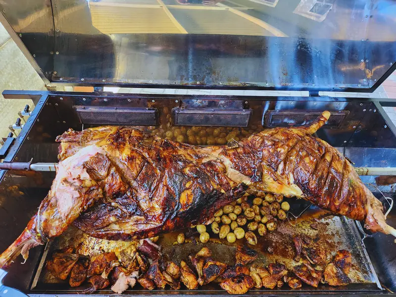 Whole lamb roasting golden-brown on a spitbraai